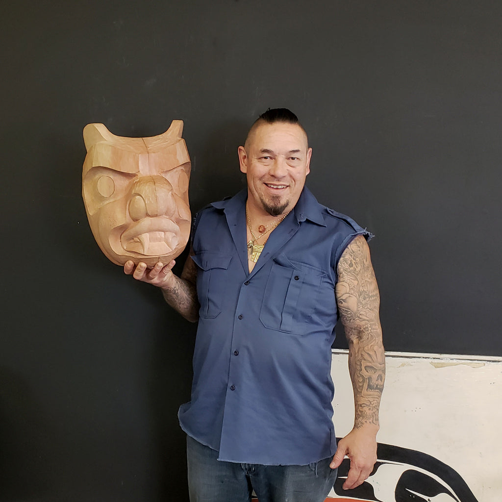 Kwakwaka'wakw artist Junior Henderson holding Carved Bear Mask in progress